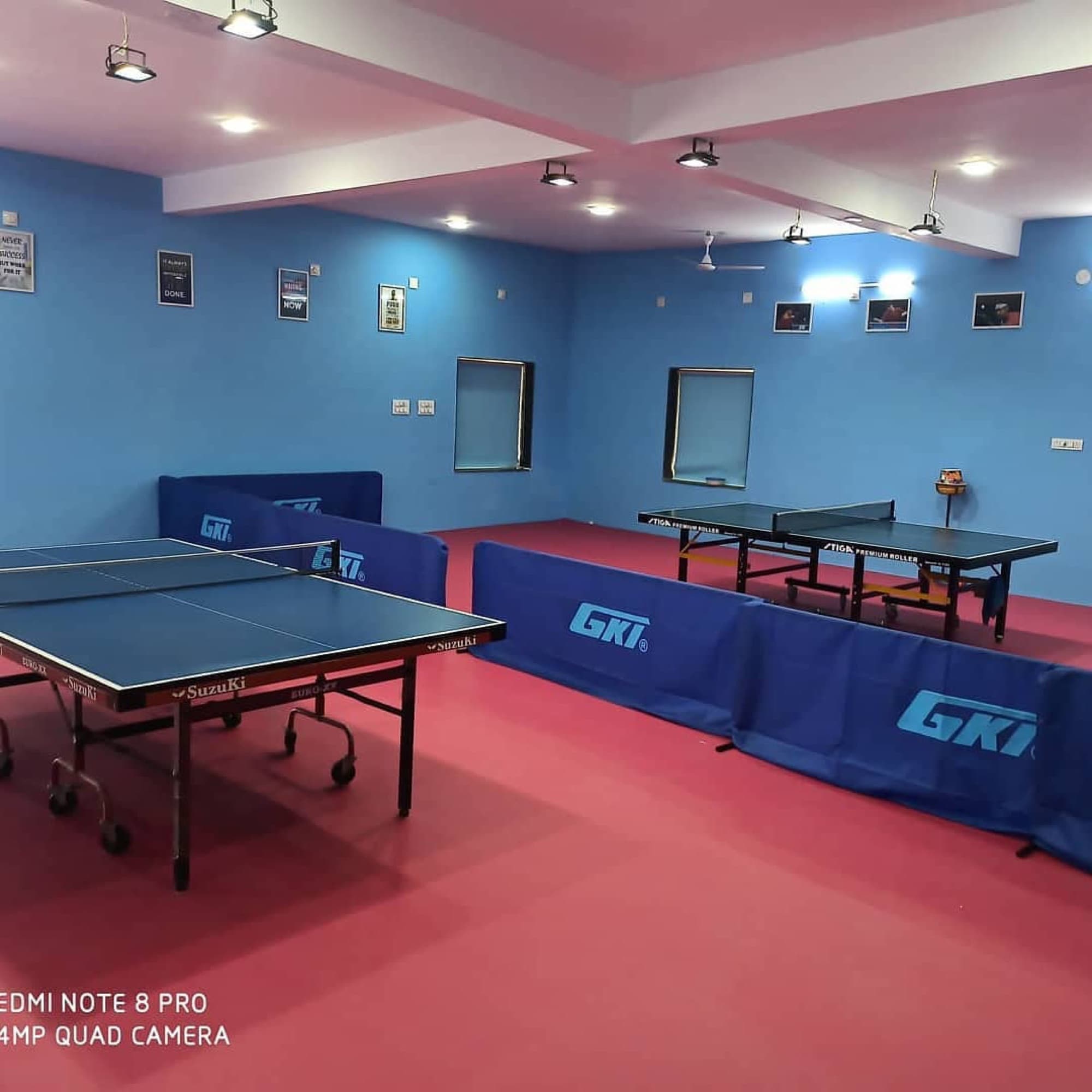 Blue match tables and red flooring inside the PSH Academy hall